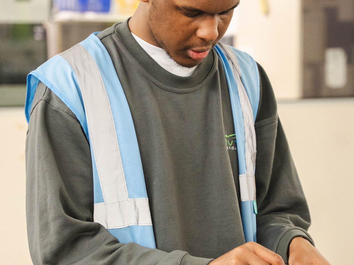 An Evtec team member in a high-visibility vest handling small components with care